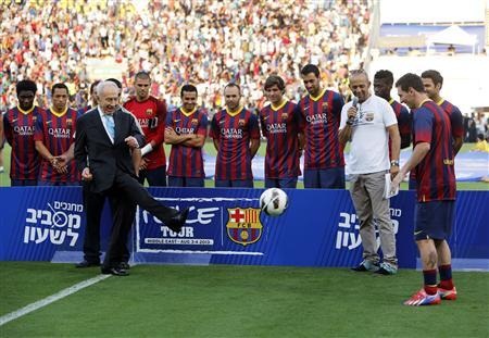 Israel President Shimon Peres (L) kicks the ball to Barcelona's Lionel Messi (R) at the opening of a soccer clinic with Arab and Jewish children at Bloomfield stadium in Tel Aviv August 4, 2013.