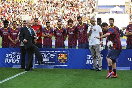 President Shimon Peres (L) kicks the ball directly into Messi's midriff