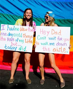 Friends Kelly Linley (left) and Katie Greiswold smile as they are photographed during a rally in support of the United States Supreme Court decision on marriage right