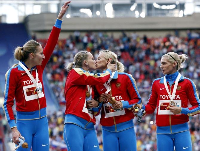 Tatyana Firova and Kseniya Ryzhova of Russia kiss on the podium as team mates Yulia Gushchina and Antonina Krivoshapka look on 