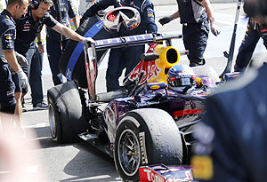 Mechanics look at the damaged tyre (back L) of Red Bull Formula One driver Sebastian Vettel of Germany during the second practice session on Friday