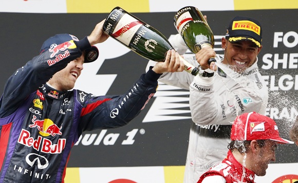 Winner Red Bull Formula One driver Sebastian Vettel of Germany (left) and third-placed Mercedes Formula One driver Lewis Hamilton pour champagne on second-placed Fernando Alonso