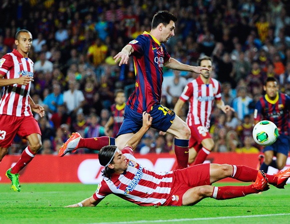 Lionel Messi of FC Barcelona duels for the ball with Filipe Luis of Atletico de Madrid