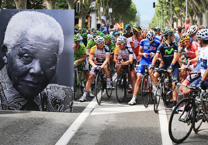 The peloton waits behind a large picture commemorating the birthday of former South African President Nelson Mandela