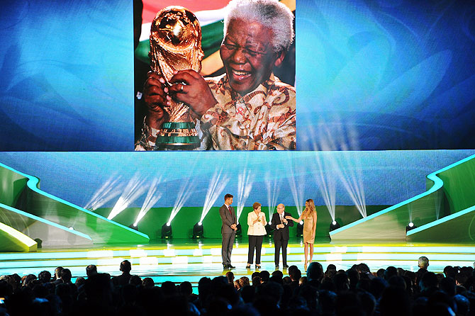 A tribute to Nelson Mandela is displayed on a screen as FIFA President Sepp Blatter, Brazil President Dilma Rousseff and hosts Fernanda Lima and Rodrigo Hilbert stand on stage before the final draw for the 2014 FIFA World Cup at Costa do Sauipe Resort, Bahia, Brazil on Friday