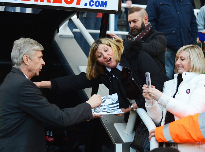 Arsene Wenger, manager of Arsenal signs an autograph