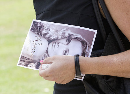A mourner leaves, holding a picture of model Reeva Steenkamp, after her memorial service at the Victoria Park Crematorium in Port Elizabeth on Tuesday