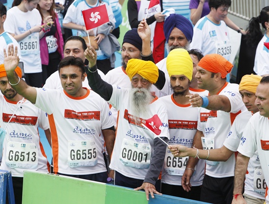 British Indian marathon runner Fauja Singh (centre), 101, carrying a Hong Kong flag, and accompanied Indian runners