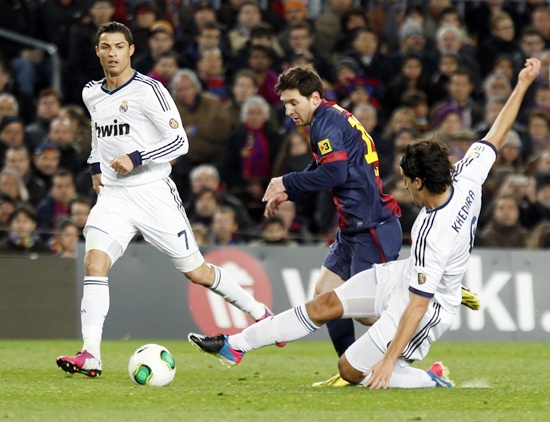 Barcelona's Lionel Messi (centre) is challenged by Real Madrid's Sami Khedira as Real Madrid's Cristiano Ronaldo (left) looks on