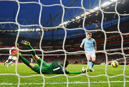 Edin Dzeko of Manchester City shoots past Wojciech Szczesny of Arsenal to score their second goal