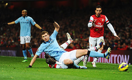 Edin Dzeko of Manchester City is tackled by Bacary Sagna of Arsenal during their Premier League match on Sunday