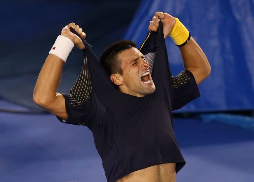 Novak Djokovic of Serbia rips his shirt off as he celebrates winning in five sets in his fourth round match against Stanislas Wawrinka of Switzerland