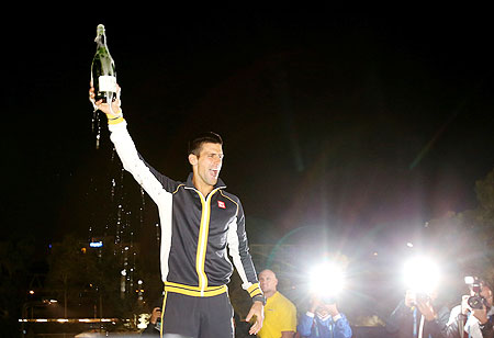 Novak Djokovic celebrates with a bottle of champagne after winning the final against Andy Murray on Sunday