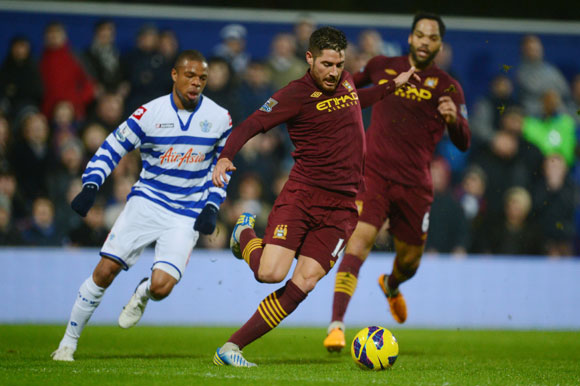 Javi Garcia of Manchester City clears the ball as Loic Remy of QPR closes in during the Premier League match at Loftus Road