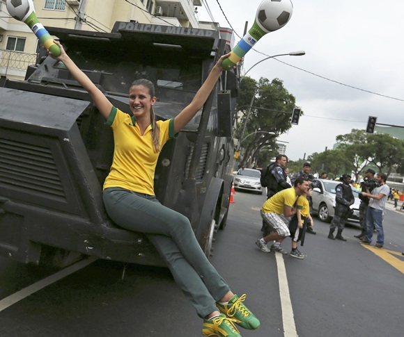 A Brazilian soccer fan poses on the riot police armoured car