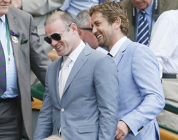 Footballer Wayne Rooney (left) and Hollywood actor Gerard Butler walk on Centre Court for the men's Wimbledon final on Sunday