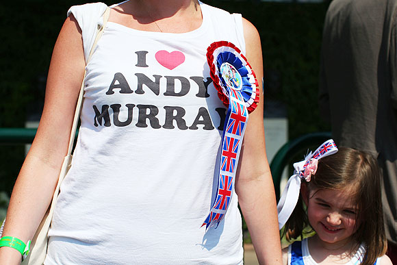 A tennis fan wears a t-shirt and rosette in support of Andy Murray
