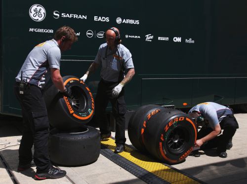 Pirelli engineers examine a set of their orange hard compound tyres in the paddock