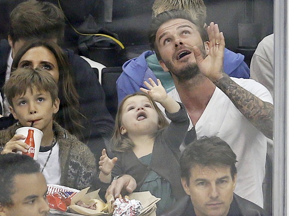 David Beckham sits behind actor Tom Cruise with his daughter Harper, 3, sons and wife Victoria