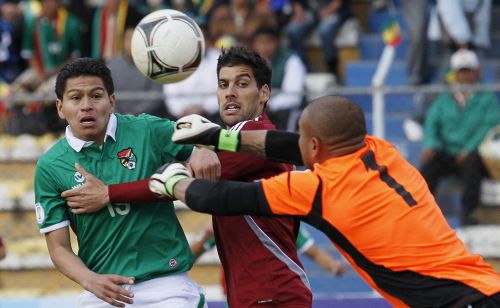Venezuela's goalkeeper Renny Vega (R) deflects the ball away from Bolivia's Carlos Saucedo (L) as Venezuela's Gabriel Cichero watches during their 2014 World Cup qualifying soccer match in La Paz
