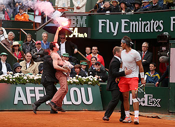 Rafael Nadal of Spain looks on as security guards restrain a protester after he lit a flare and ran on court during the men's singles final on Sunday