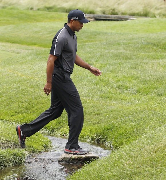 Tiger Woods of the US crosses a creek