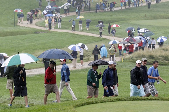 Spectators walk in the rain during the US Open golf championship at the Merion Golf Club in Ardmore