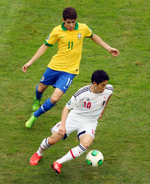 Japan's Shinji Kagawa gets the ball past Oscar of Brazil