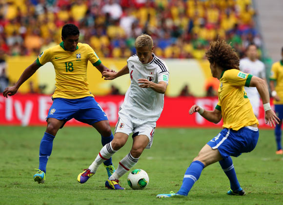 Japan's Keisuke Honda tries to get the ball past Paulinho and David Luiz of Brazil