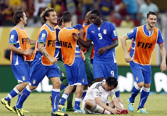 Italy's Mario Balotelli (9) celebrates with teammates as Japan's Shinji Okazaki reacts