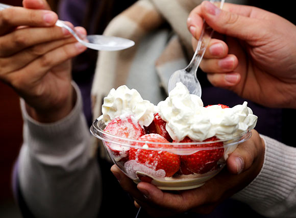 Spectators enjoy a bowl of strawberries and cream