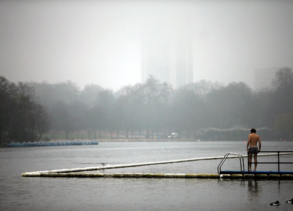 A man prepares for a foggy morning swim in the Serpentine Lake in Hyde Park, in London.