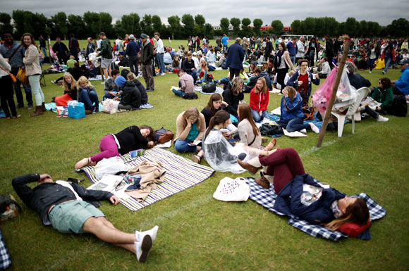 Non-ticket holders wait in line in a field outside Wimbledon