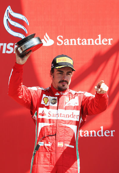 Fernando Alonso of Spain and Ferrari celebrates on the podium after finishing third