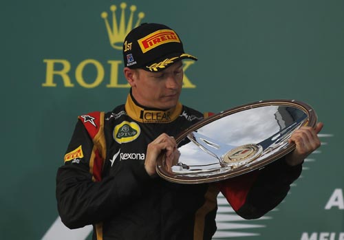 Lotus Formula One driver Kimi Raikkonen of Finland looks at his trophy after winning the Australian F1 Grand Prix at the Albert Park circuit in Melbourne