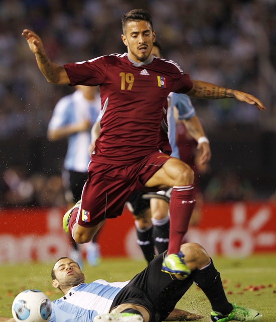 Venezuela's  Frank Feltscher (top) jumps over Argentina's Javier Mascherano