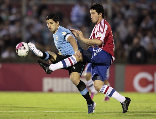 Paraguay's Cristian Riveros (right) fights for the ball with Uruguay's Luis Suarez