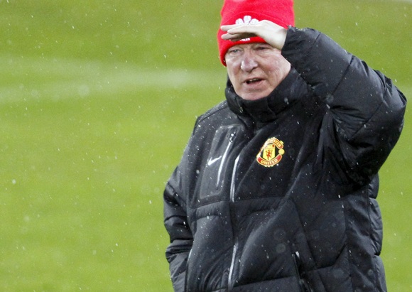 Manchester United manager Alex Ferguson stands in the rain during a team training session