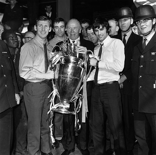 Manchester United manager Matt Busby (centre) holding the European Cup trophy with players Pat Crerand (left) and George Best, at Euston Station, on their way back to Manchester after beating Benfica 4-1 in the final at Wembley. On the right are security men who will guard the trophy during the journey on 30th May, 1968
