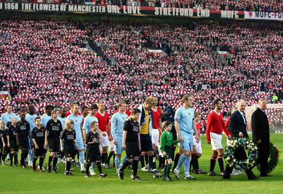 The Manchester United team (red) and Manchester City teams enter the pitch