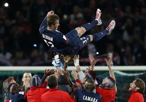 Paris Saint-Germain players throw David Beckham in the air at the end of their team's French Ligue 1 soccer match against Brest at the Parc des Princes stadium in Paris