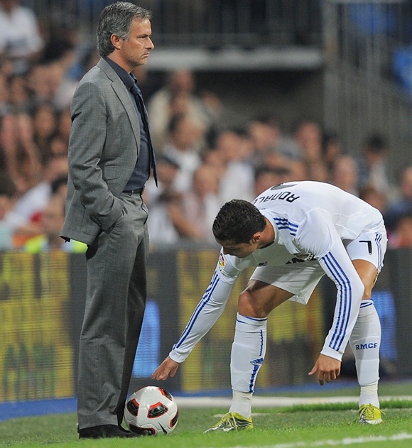 Cristiano Ronaldo of Ral Madrid picks up the ball at the feet of Real manager Jose Mourinho