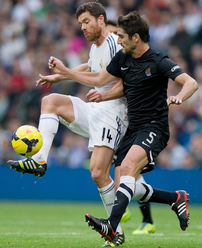 Xabi Alonso (left) of Real Madrid CF competes for the ball with Markel Bergara (right) of Real Sociedad