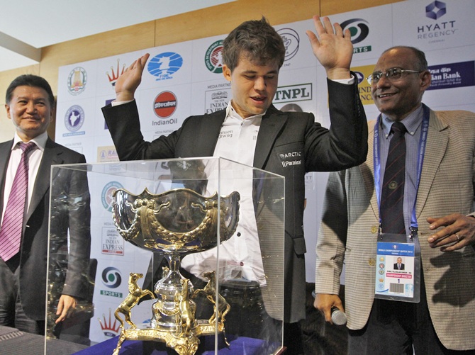 Norway's Magnus Carlsen (centre) gestures next to his trophy after clinching the FIDE World Chess Championship in Chennai