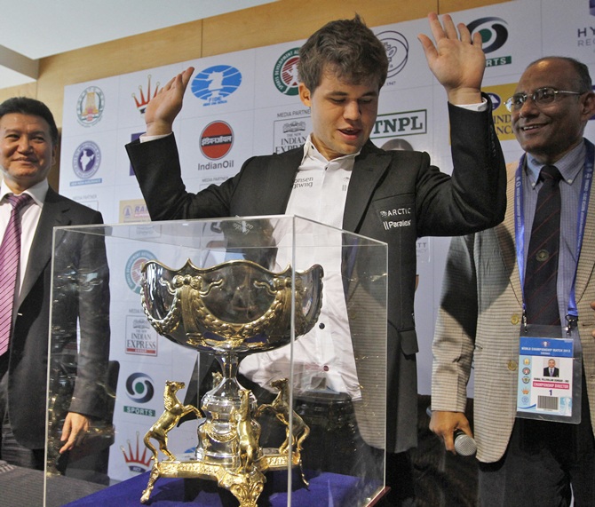 Norway's Magnus Carlsen (centre) gestures next to his trophy after clinching the FIDE World Chess Championship in Chennai