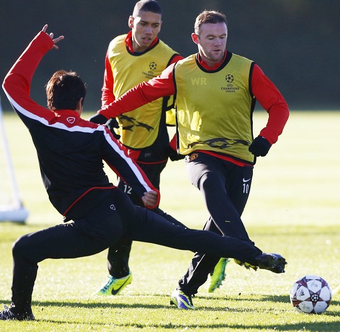Manchester United's Shinji Kagawa challenges teammate Wayne Rooney (right) during a training session