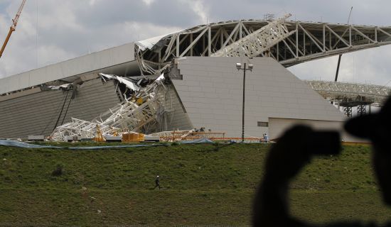 A man takes a picture of a crane that collapsed on the site of the Arena Sao Paulo stadium
