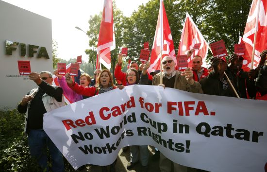 Members of the Swiss UNIA workers union display red cards and shout slogans during a protest in front of the headquarters of soccer's international governing body FIFA