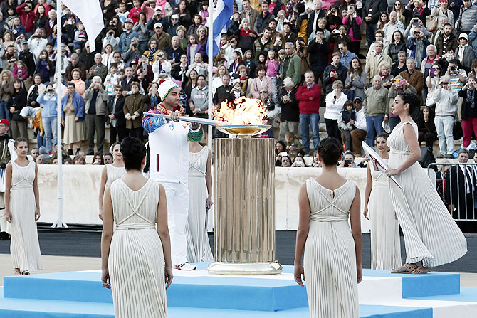 Greek figure skater Panagiotis Markouzios lights an altar with an Olympic torch of the Sochi 2014 Winter Games during a handover ceremony at the Panathenean stadium in Athens on Saturday