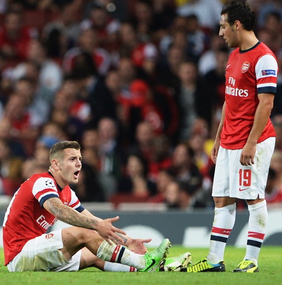 Jack Wilshere of Arsenal clutches his ankle after a tackle